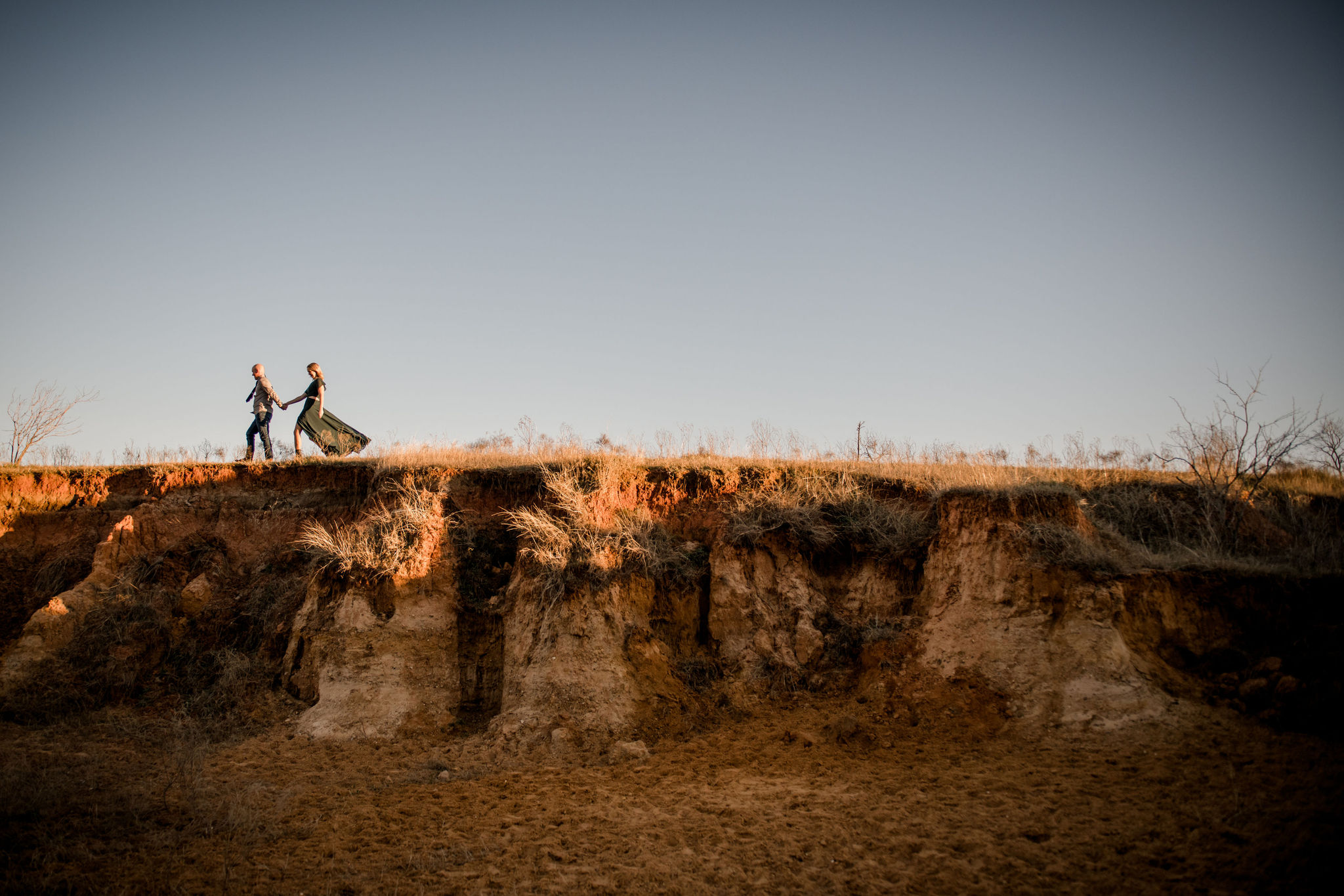 Wide angle photograph of a couple walking over the top of a cliff in West Texas photo by Wedding Photographer in Houston, Jamie Hardin Photography