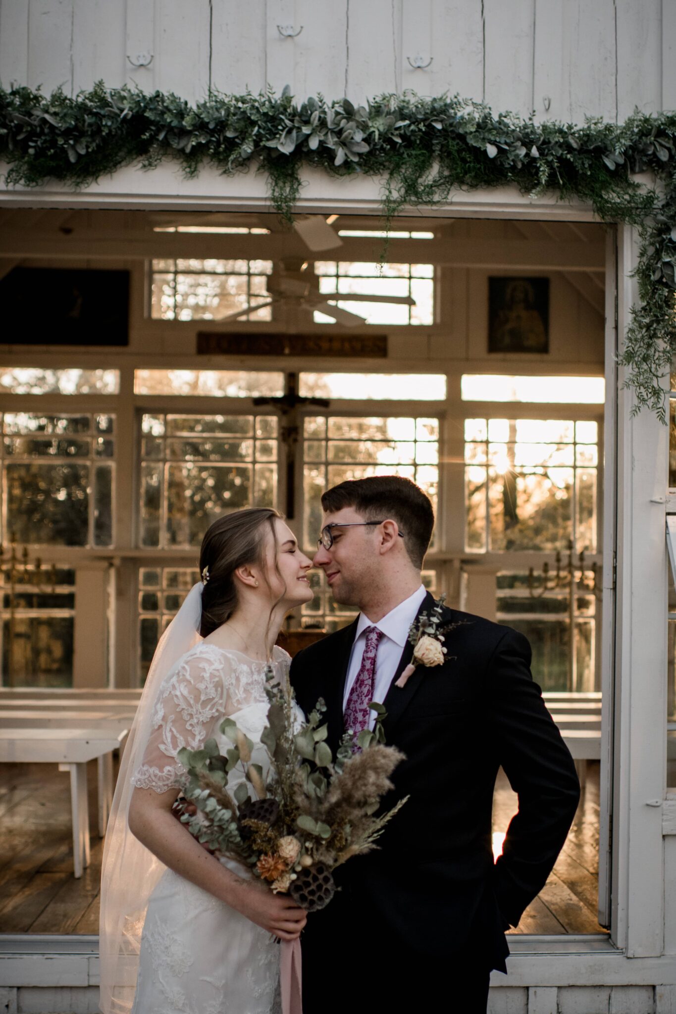 the texas bride and groom go in for a kiss during their bride and groom portraits in front of the 7F lodge in golden hours