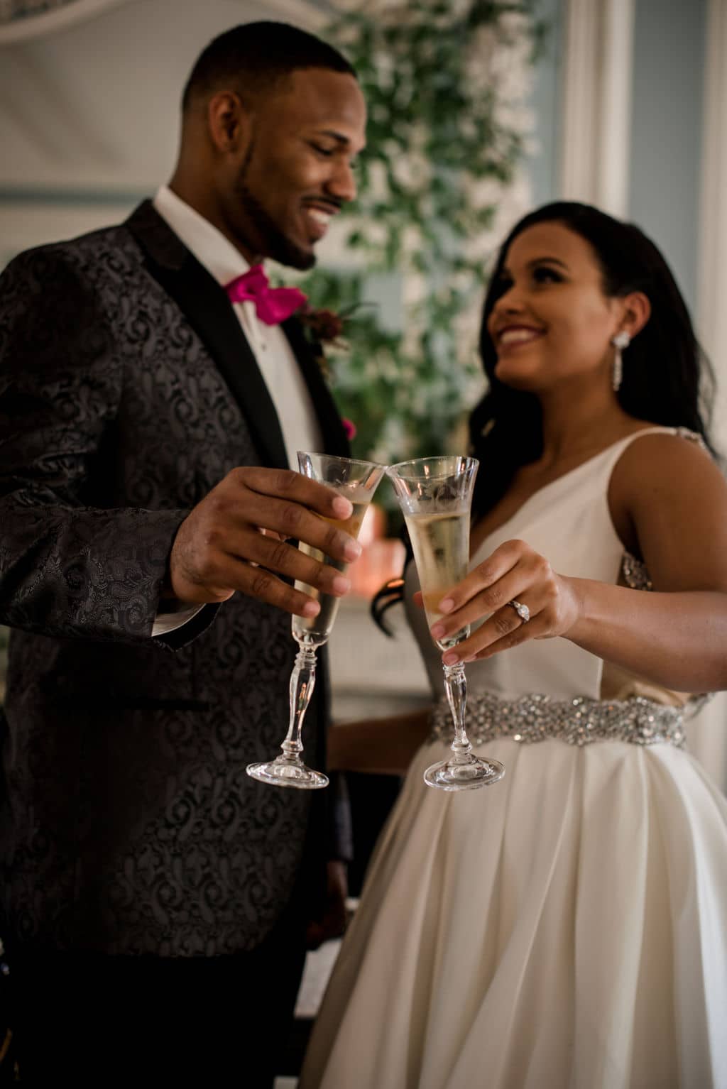 the texas bride and groom share a glass of champagne inside the ballroom of the inn at the Astin Mansion.