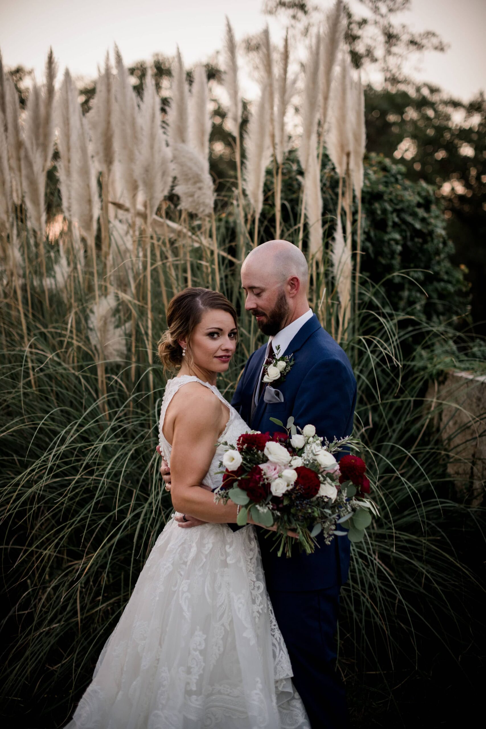 the texas bride and groom share a dance in the courtyard of the inn at quarry ridge where they stand in front of cat tails