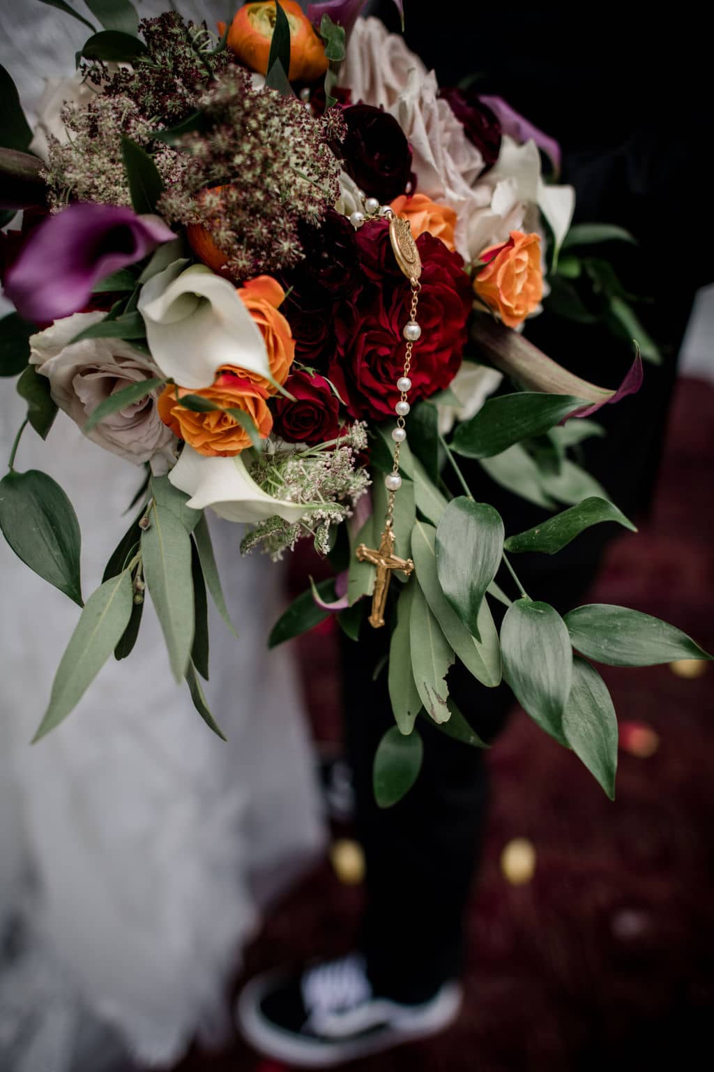 the bride's wedding bouquet with deep dark tones is displayed while the bride and groom are walking down 7F Lodge's chapel stairs