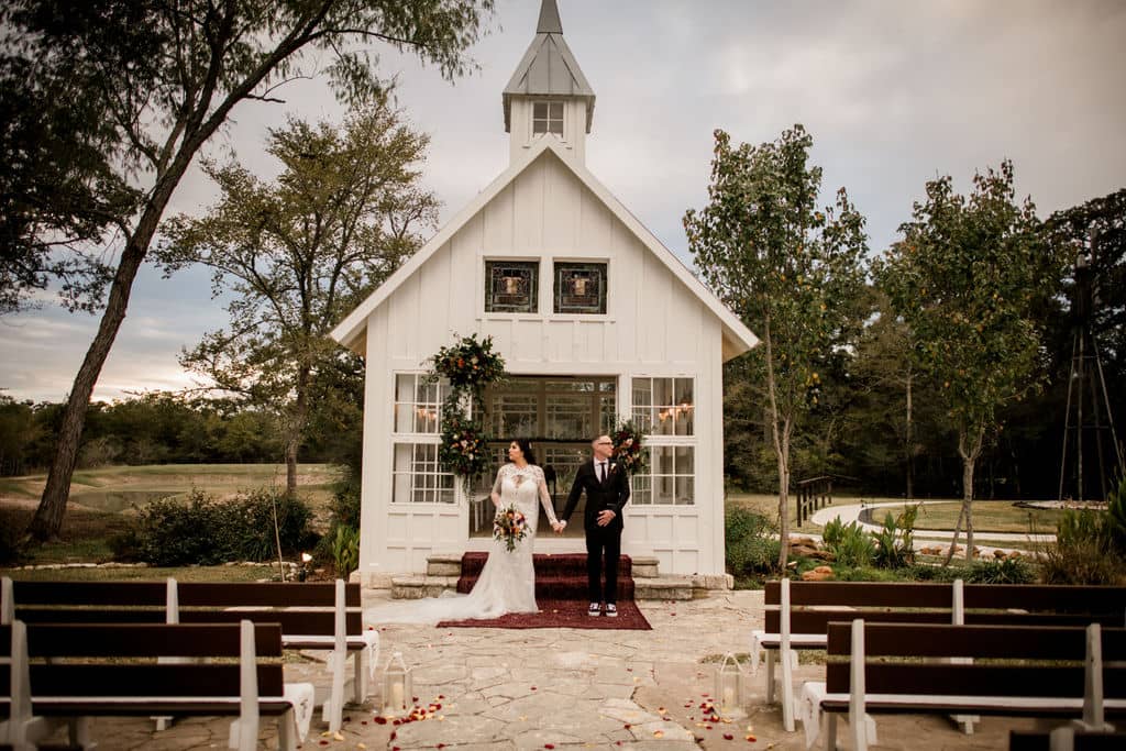 the texas bride and groom stand in front of 7F Lodge's white chapel