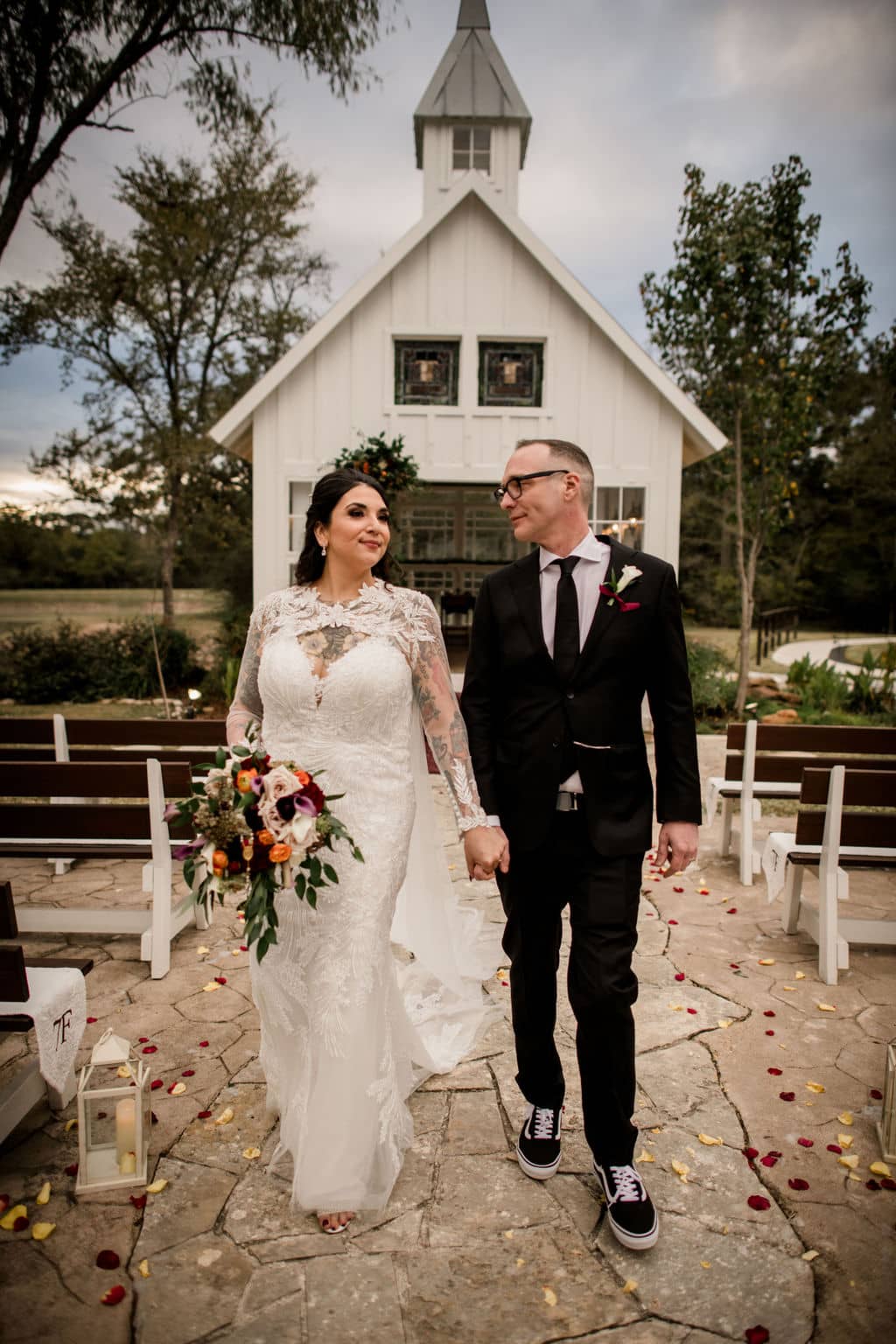 the texas bride and groom walk down the aisle as newlyweds in front of 7F Lodge's white chapel for their wedding in the Bryan-College Station