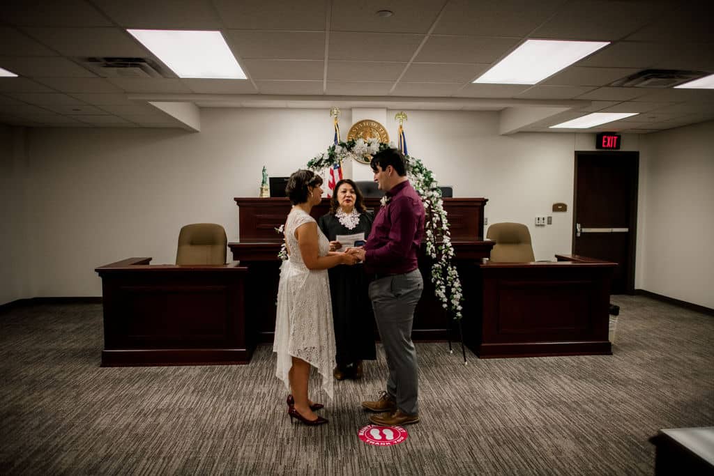 the texas bride and groom stand in front of the justice's altar at the brazos county courthouse