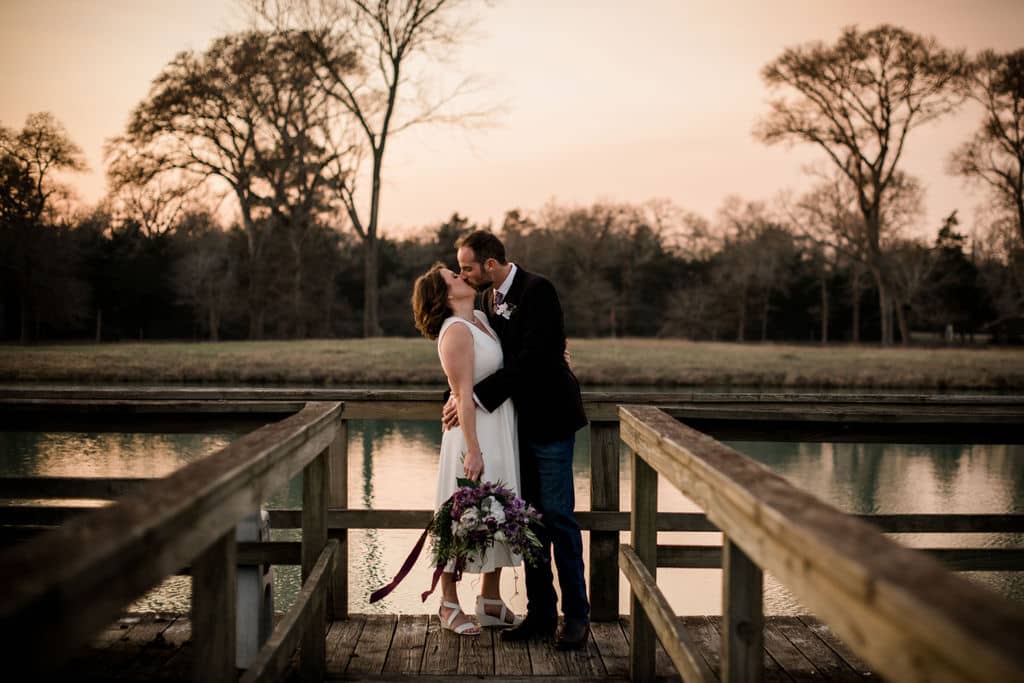 the texas newlyweds share a kiss at the end of the dock overlooking a lake at their airbnb elopement
