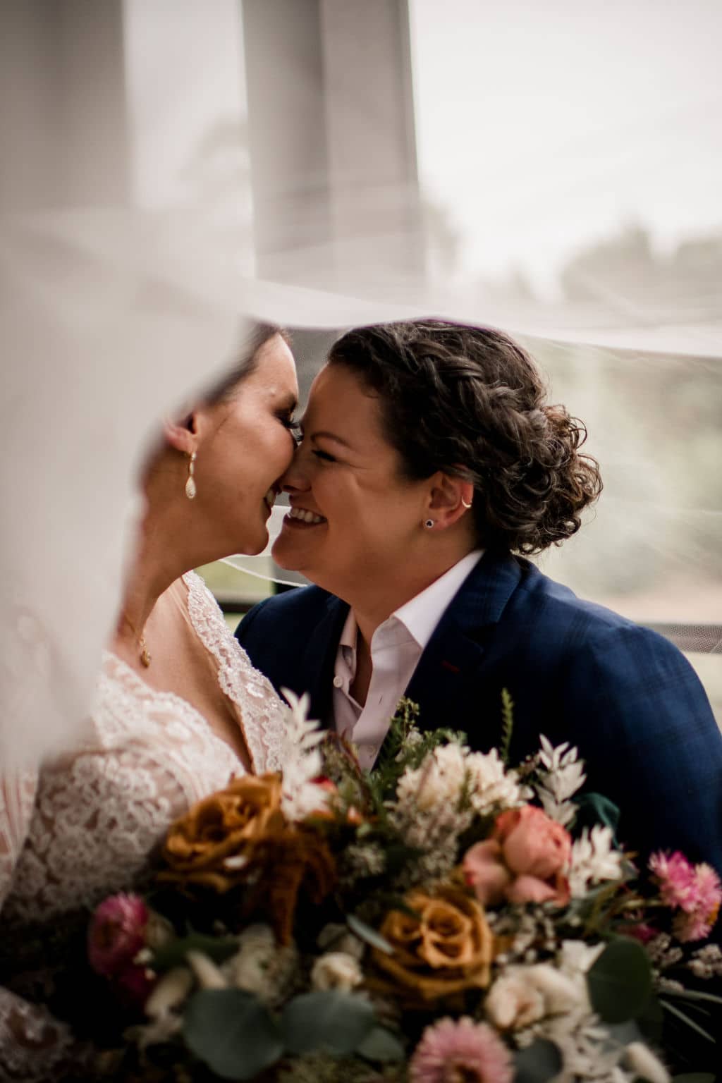 As a bryant-college station photographer, photographed are two brides under a veil about to kiss in my inclusive client experience