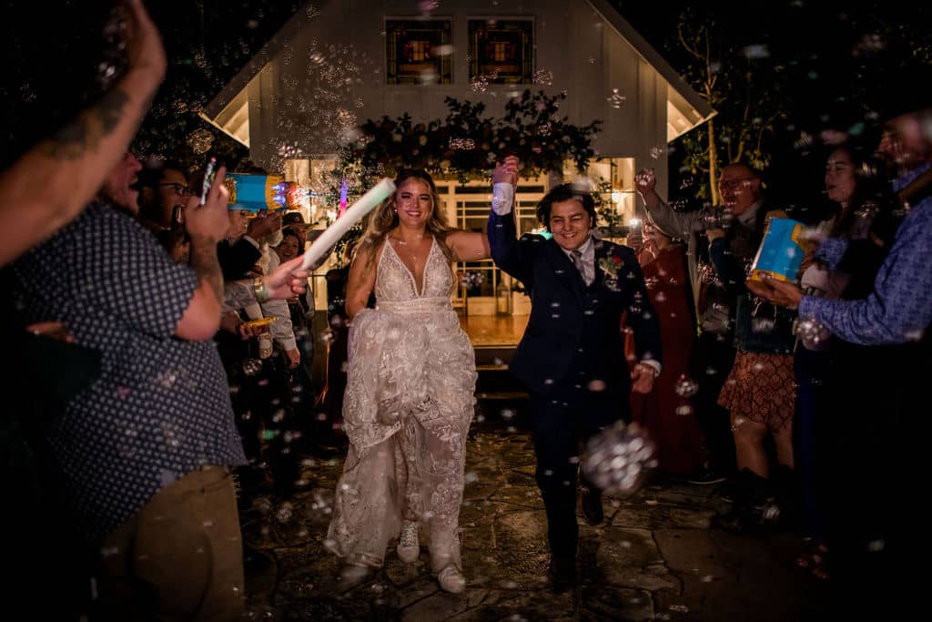 The bride and groom leave 7F Lodge in Texas surrounded by bubbles as a unique wedding exit captured by Jamie Hardin Photography