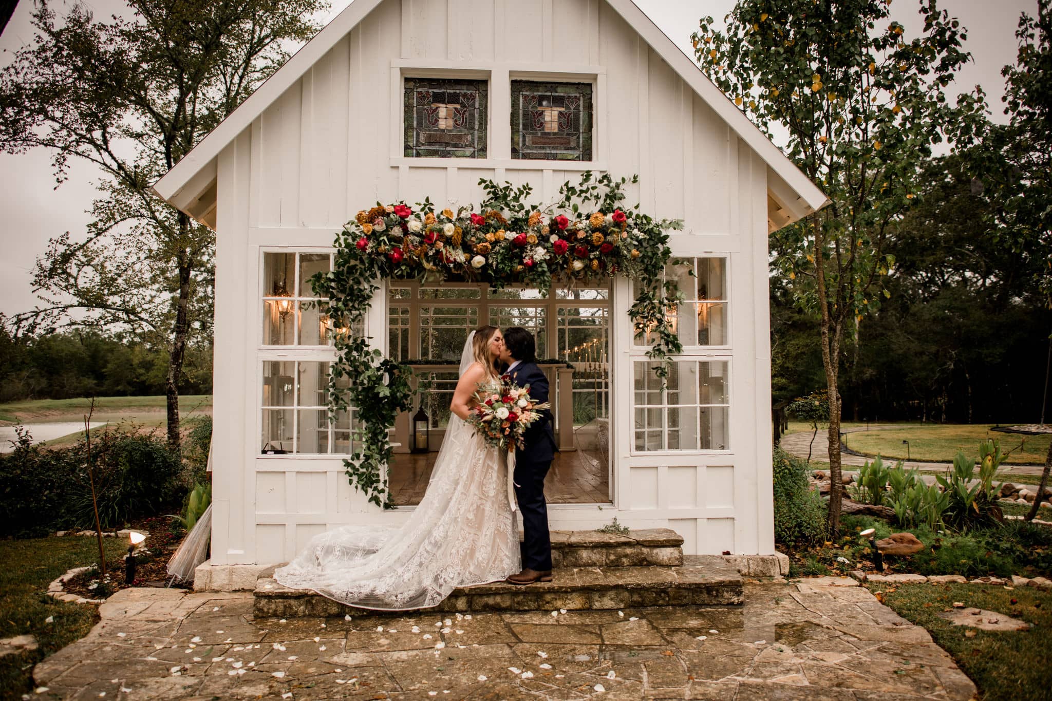 bride and groom kissing in front of the popular white chapel of 7F Lodge and Events in College Station, texas