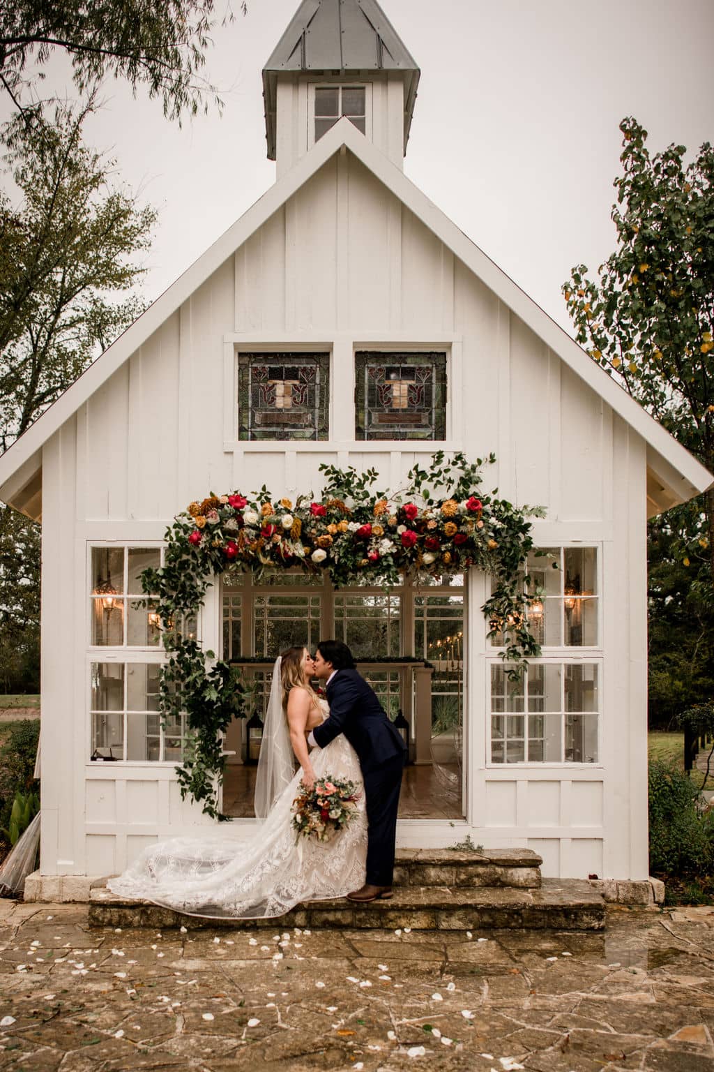 bride and groom kissing in front of the popular white chapel of 7F Lodge and Events in College Station, texas