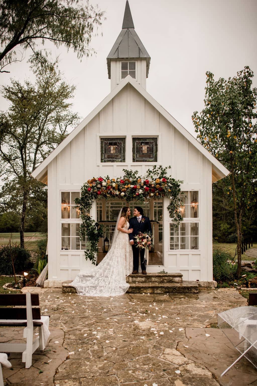 bride and groom standing in front of the popular white chapel of 7F Lodge and Events in College Station, texas