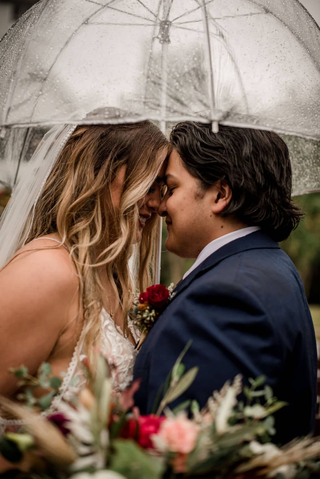 bride and groom being intimate touching forehead under and umbrella