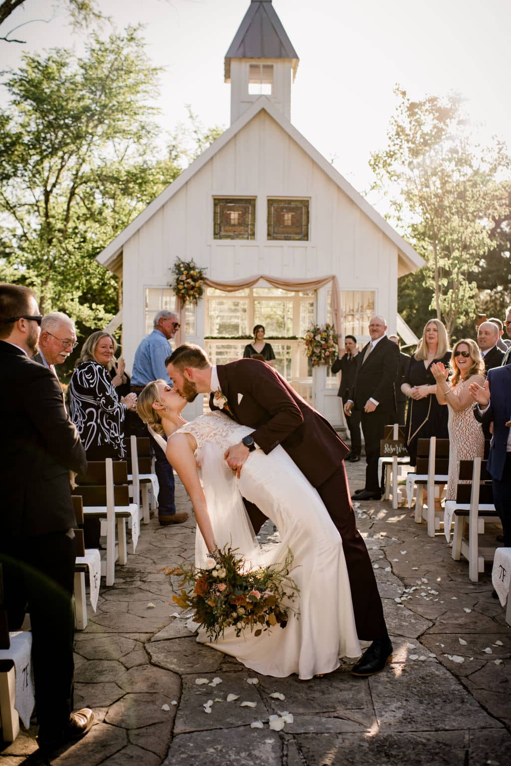 bride and groom kissing in front of the popular white chapel of 7F Lodge and Events in College Station, texas