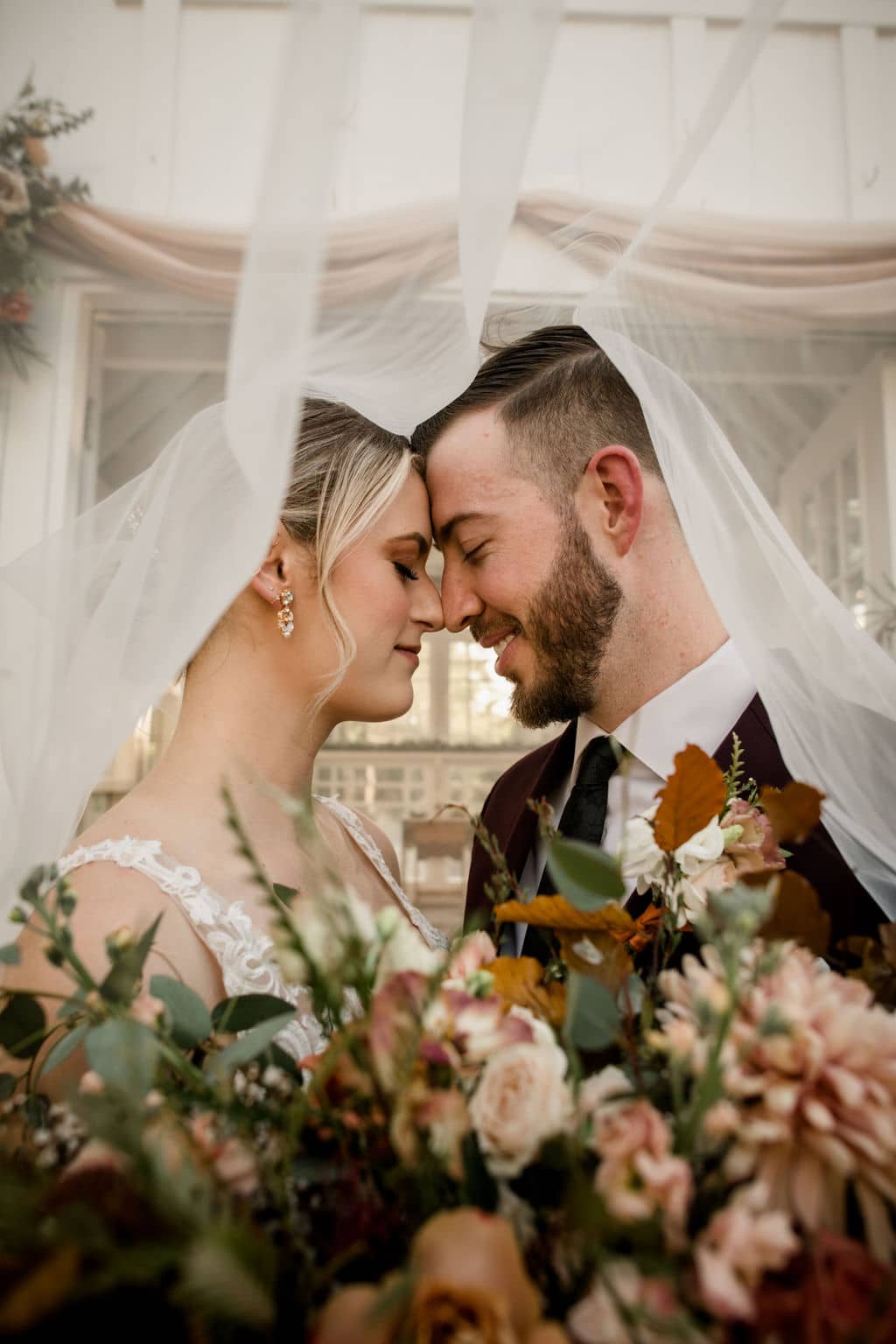 bride and groom being very intimate touching foreheads under the veil