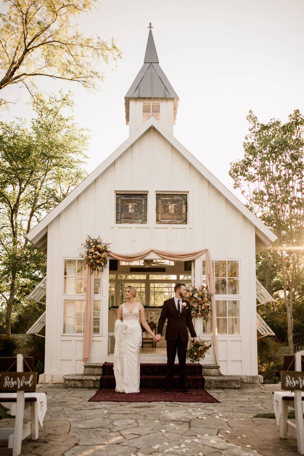 bride and groom standing in front of the popular white chapel of 7F Lodge and Events in College Station, texas