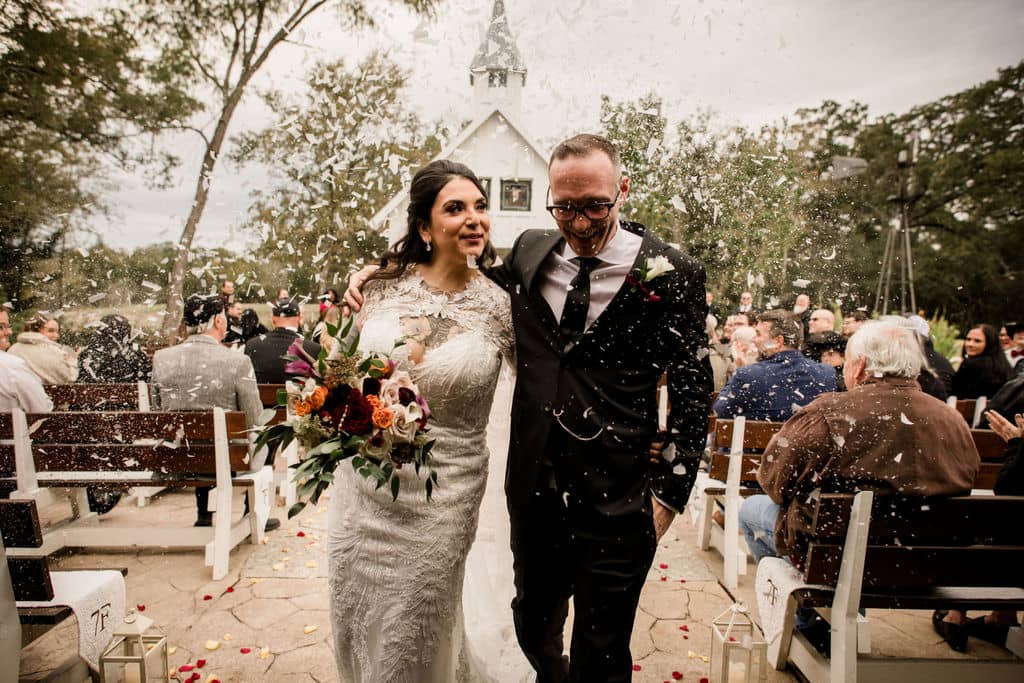 The bride and groom exiting 7F Lodge in Texas surrounded by confetti as their unique wedding exit is captured by Jamie Hardin Photography