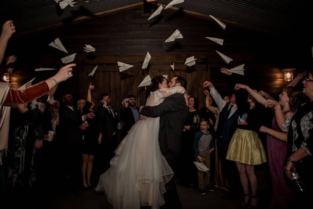 Peach Creek in Texas surrounded by paper planes as a unique wedding exit for the bride and groom as they kiss captured by Jamie Hardin Photography