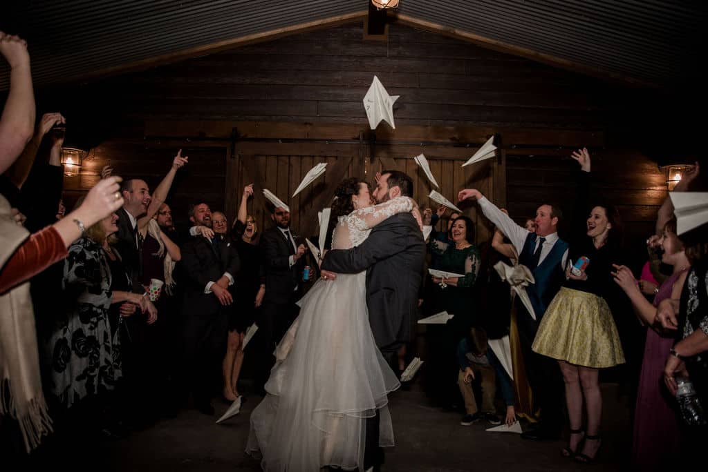 Peach Creek in Texas surrounded by paper planes as a unique wedding exit for the bride and groom as they kiss captured by Jamie Hardin Photography