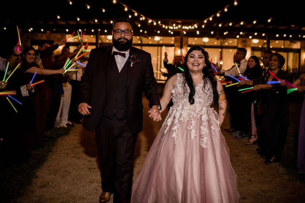 The bride and groom exiting their wedding surrounded by glow sticks as a unique wedding exit captured by Jamie Hardin Photography
