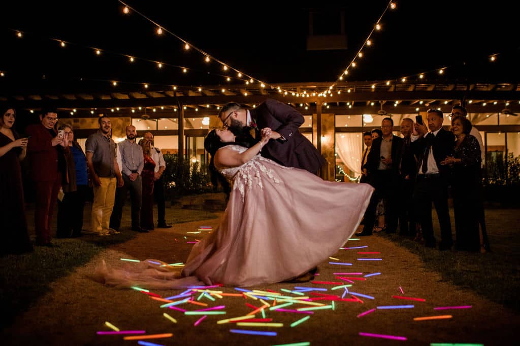 In Texas the bride and groom kissing surrounded by glow sticks as a unique wedding exit captured by Jamie Hardin Photography