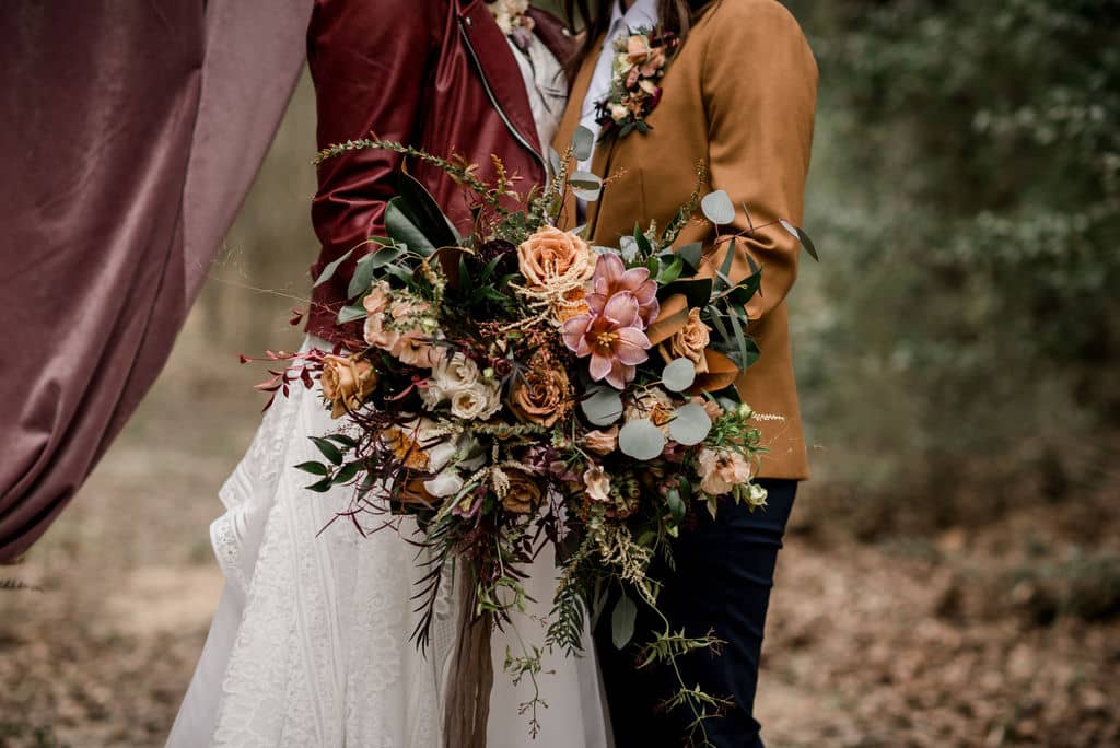 two brides stand at the alter of their wedding day surrounded by florals by a texas wedding florist