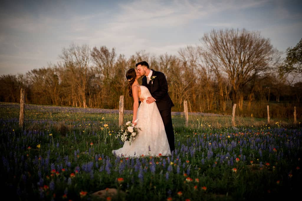 Bride and groom are kissing in a field in bryan college station texas after their wedding.