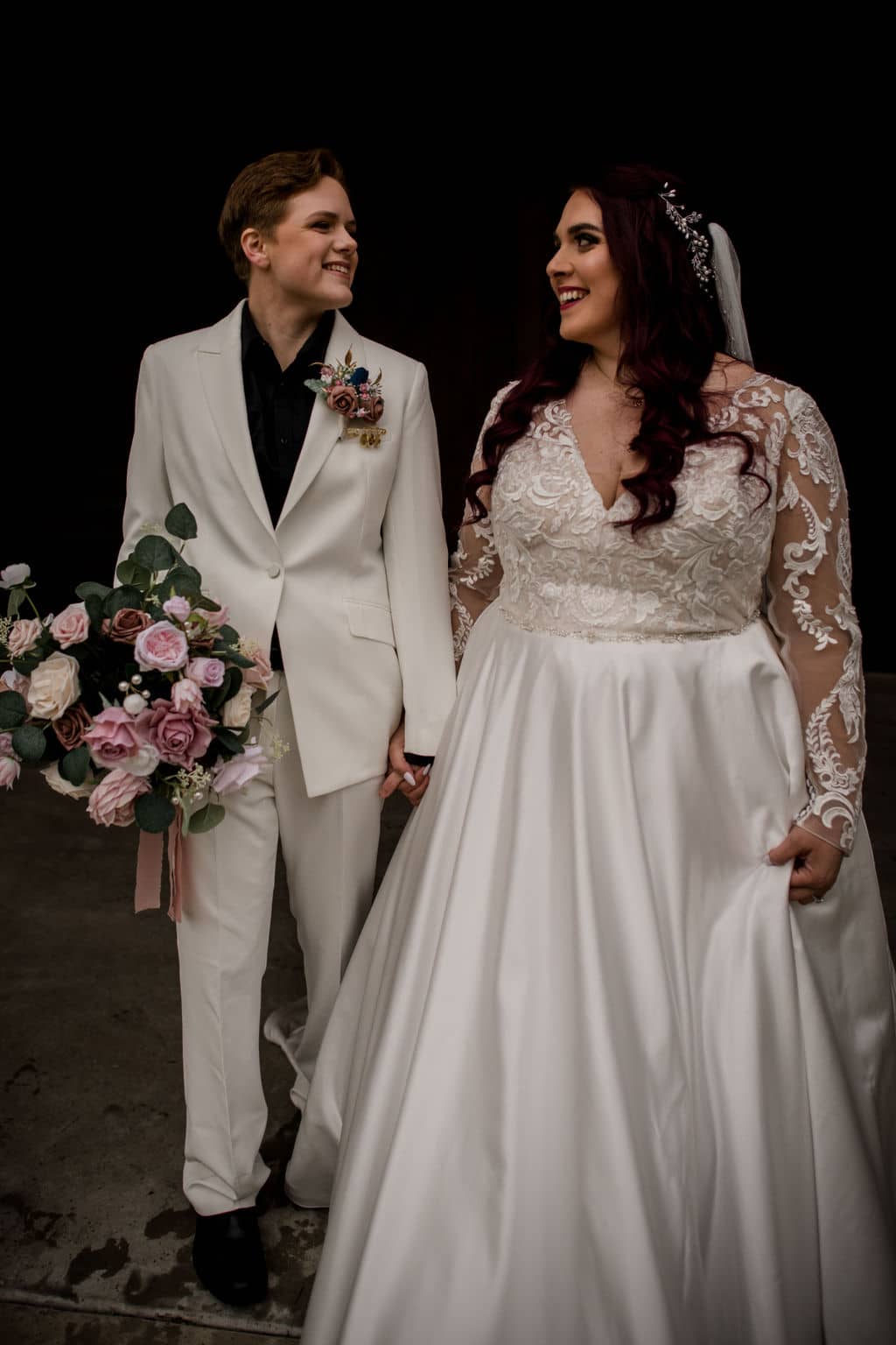 the two brides are holding hands walking down the venue