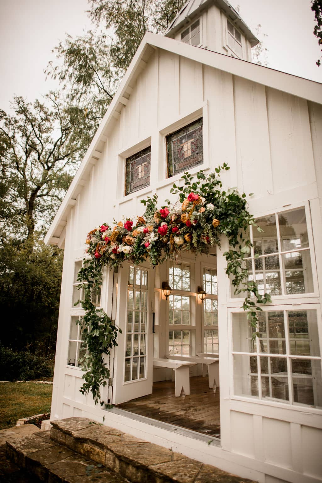 the floral arch is covering the entrance to the white chapel of 7f lodge designed by a texas wedding florist