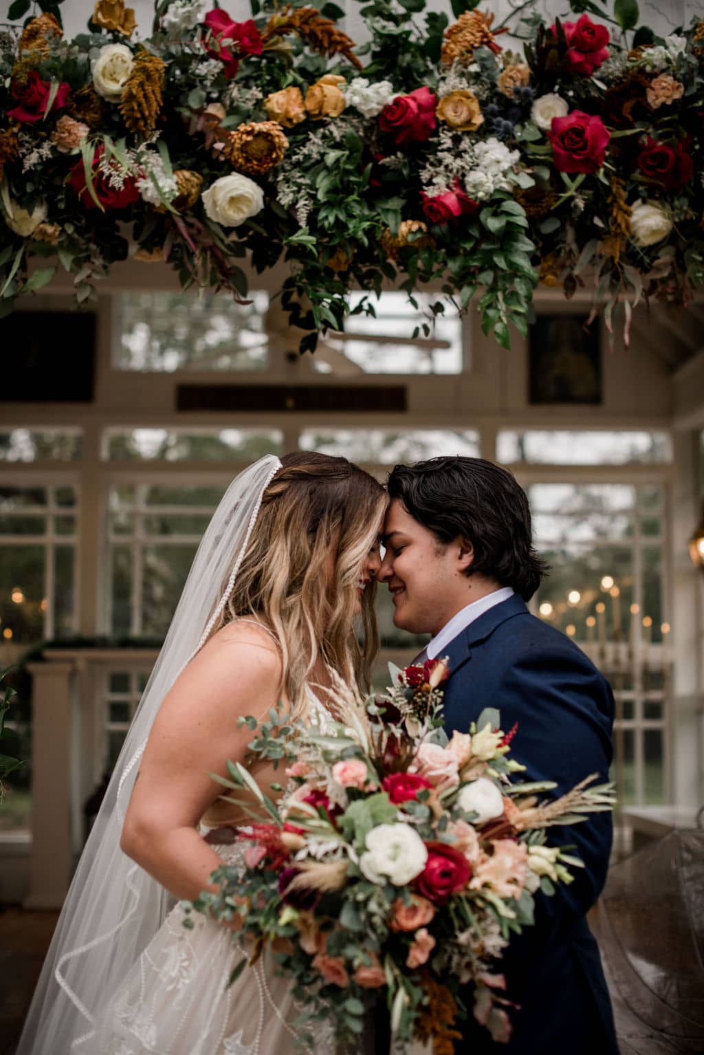 the bride and groom are under a floral arch at 7f lodge while holding up the bridal bouquet designed by urban rubbish