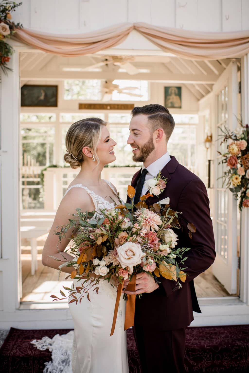 the bride and groom are posed staring at each other in front of the white chapel at 7f lodge