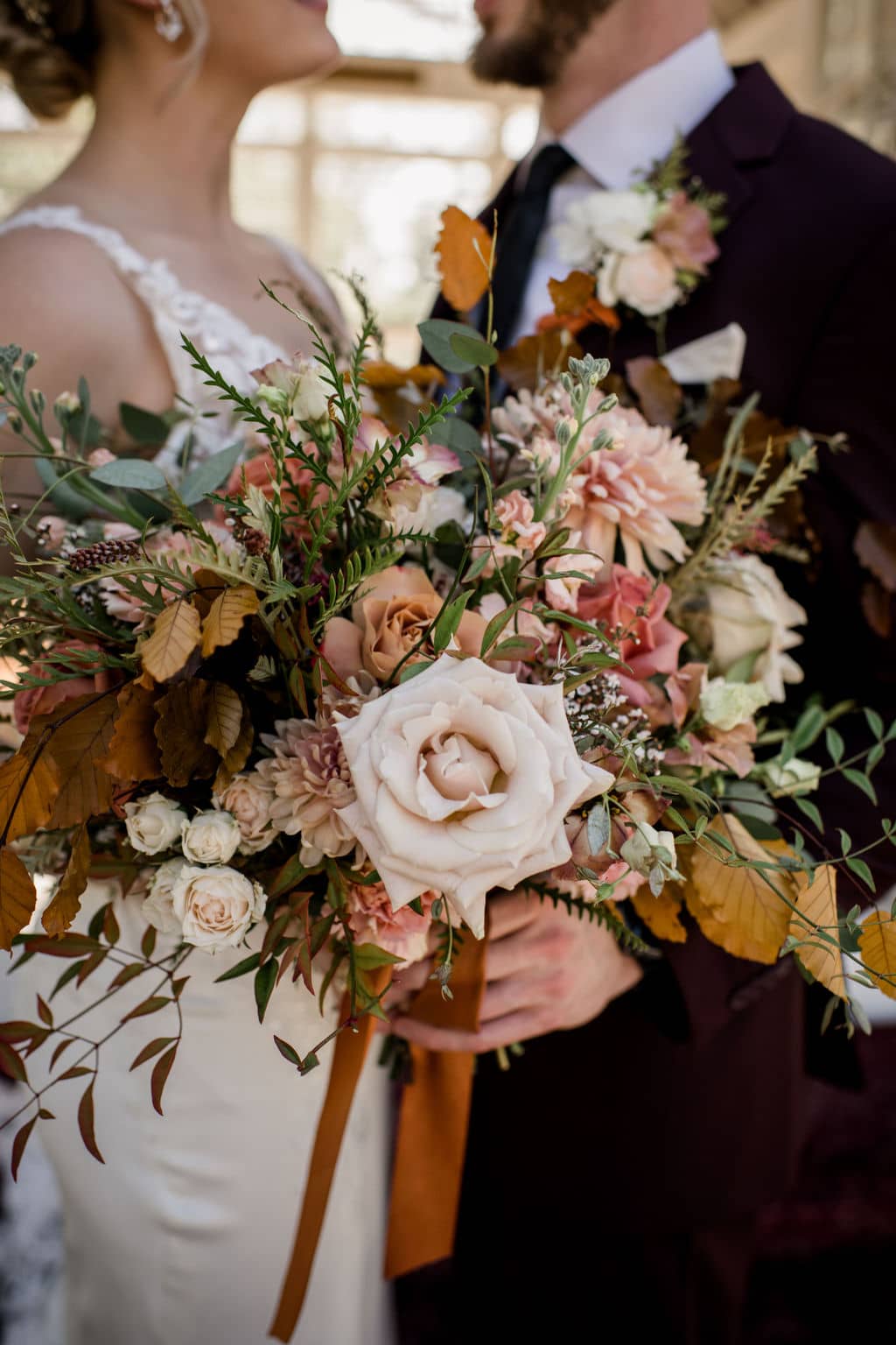 the texas bride and groom are standing behind an intricate bouquet done by a texas wedding florist