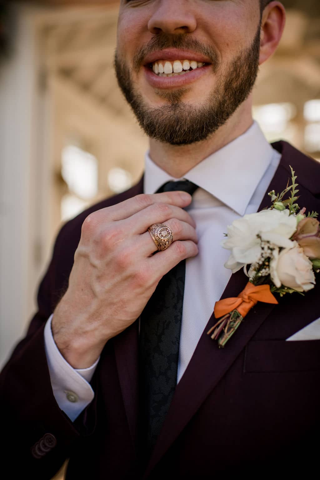 a close up of the groom adjusting his tie
