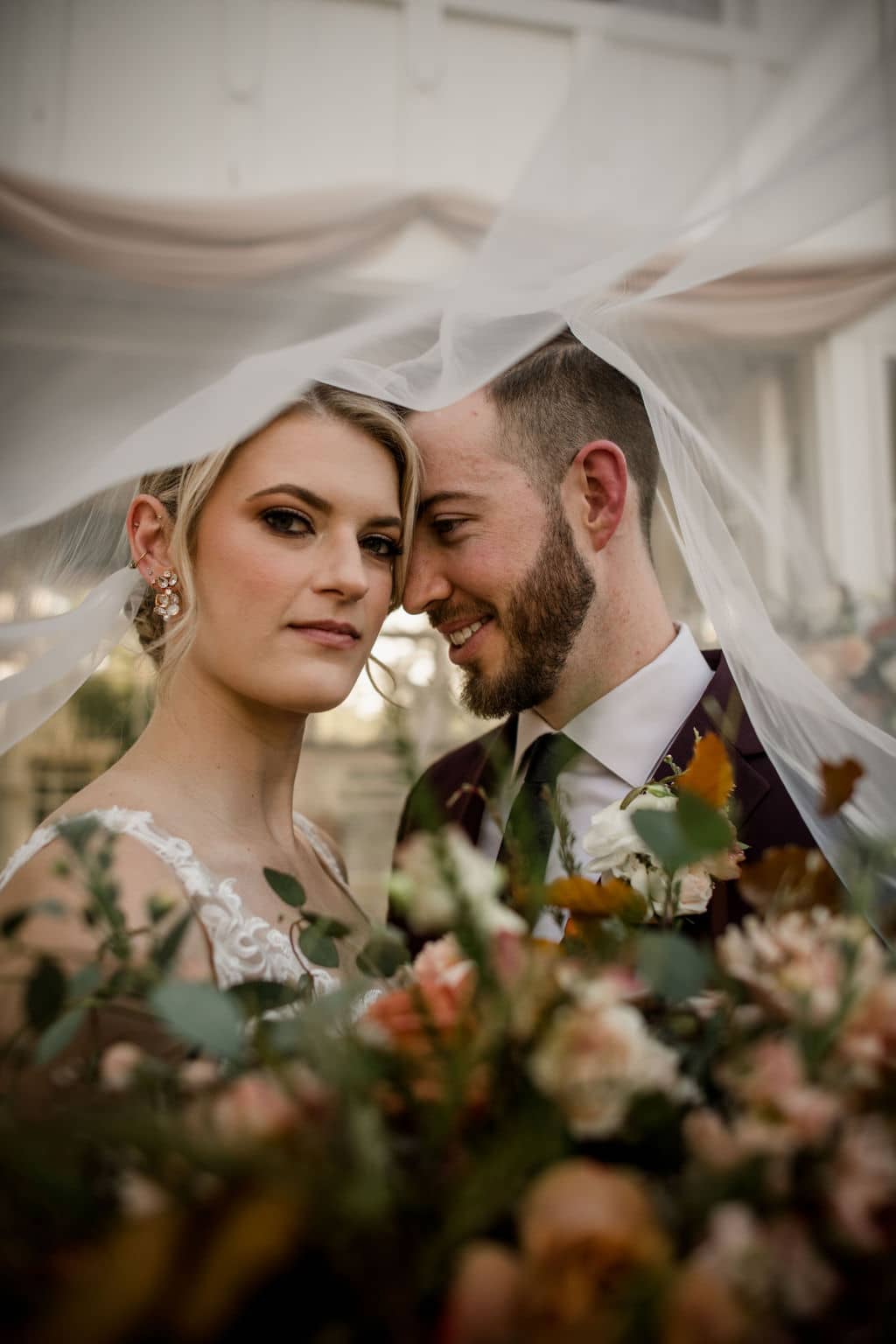 in learning how to plan a wedding in bryan college station, the bride opted for a veil from a local wedding vendor. Which the bride and groom are now posed under