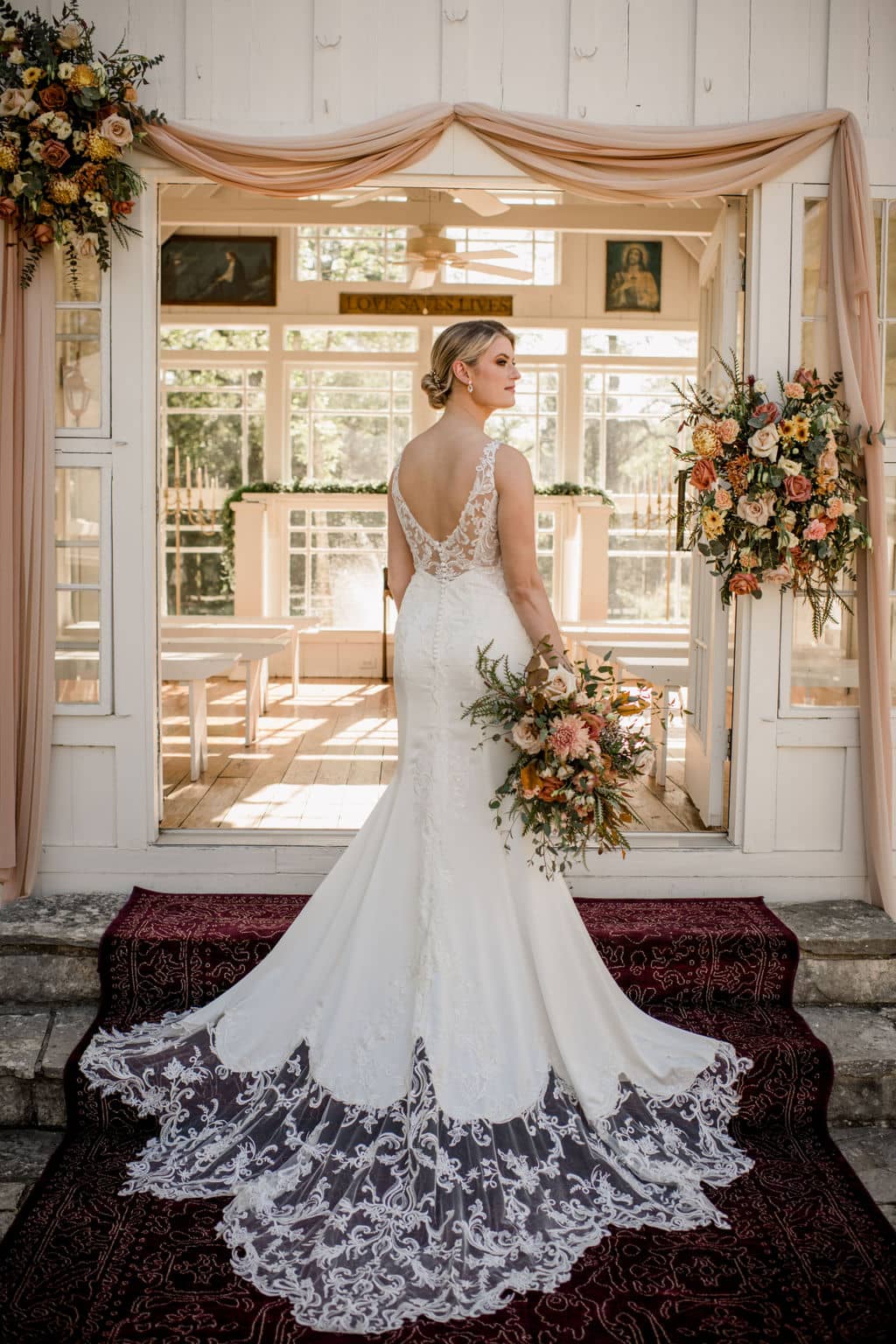 the bride is posing in her white wedding dress in front of the white chapel at 7F lodge