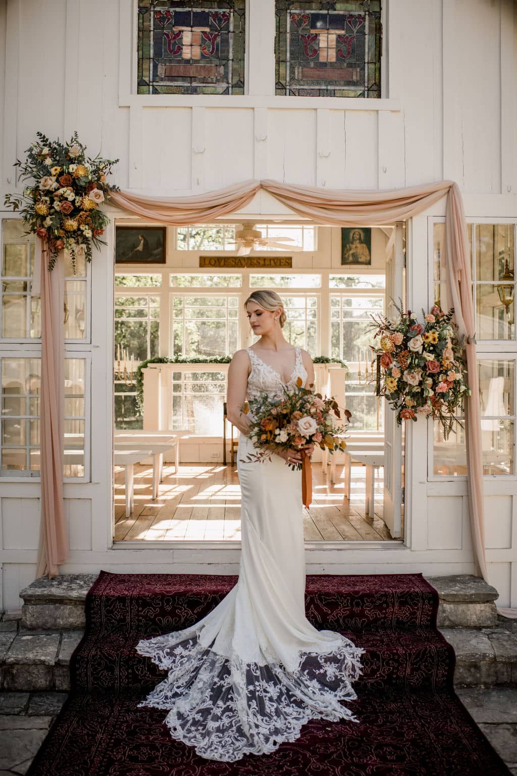 the texas bride is holding her bridal bouquet made by urban rubbish and is surrounded by an arch of florals