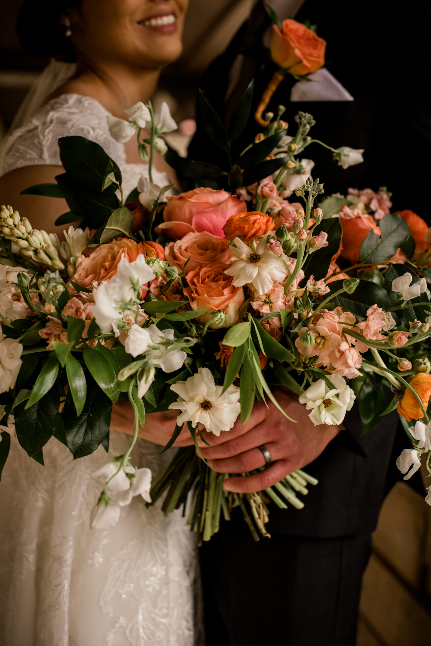 the groom is holding the bride's seasonal summer floral bouquet