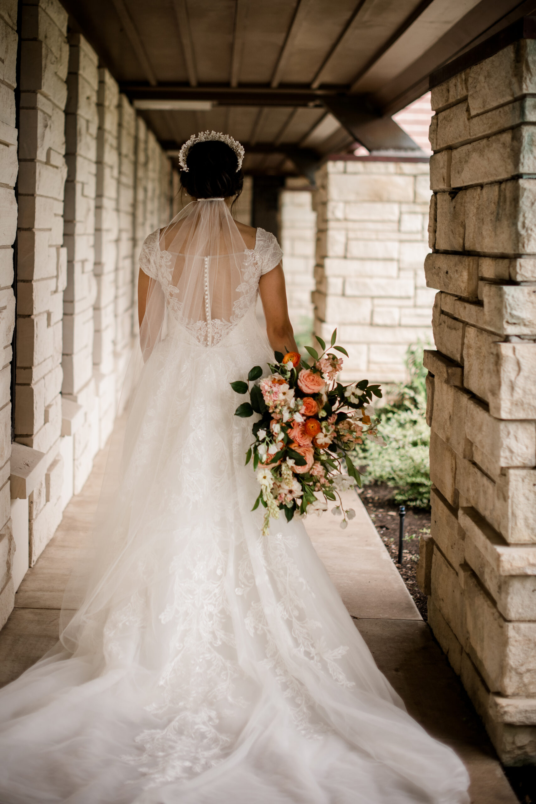 the bride is walking down the church hall ways holding her seasonal summer floral bouquet