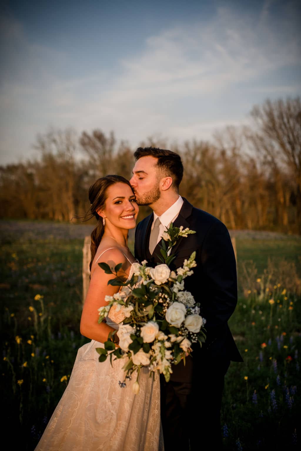 bride and groom kissing in the middle of a wild flower field in byran college station texas after their wedding