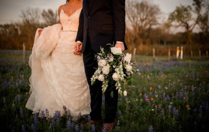 Bride and groom walking in a field in bryan college station texas after their wedding.
