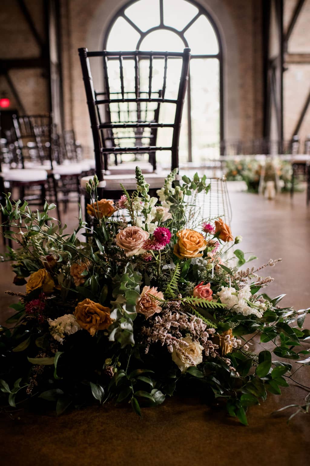 the chairs in the church are marked with floral arrangements on the floor made by Texas wedding florist Urban rubbish