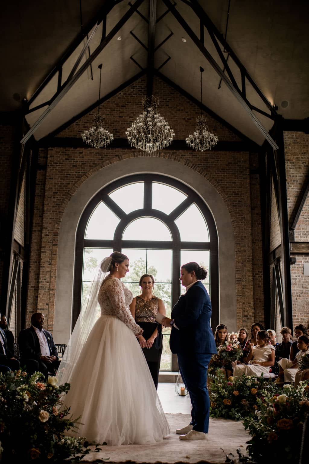 two brides stand at the alter of their wedding day surrounded by florals by a texas wedding florist