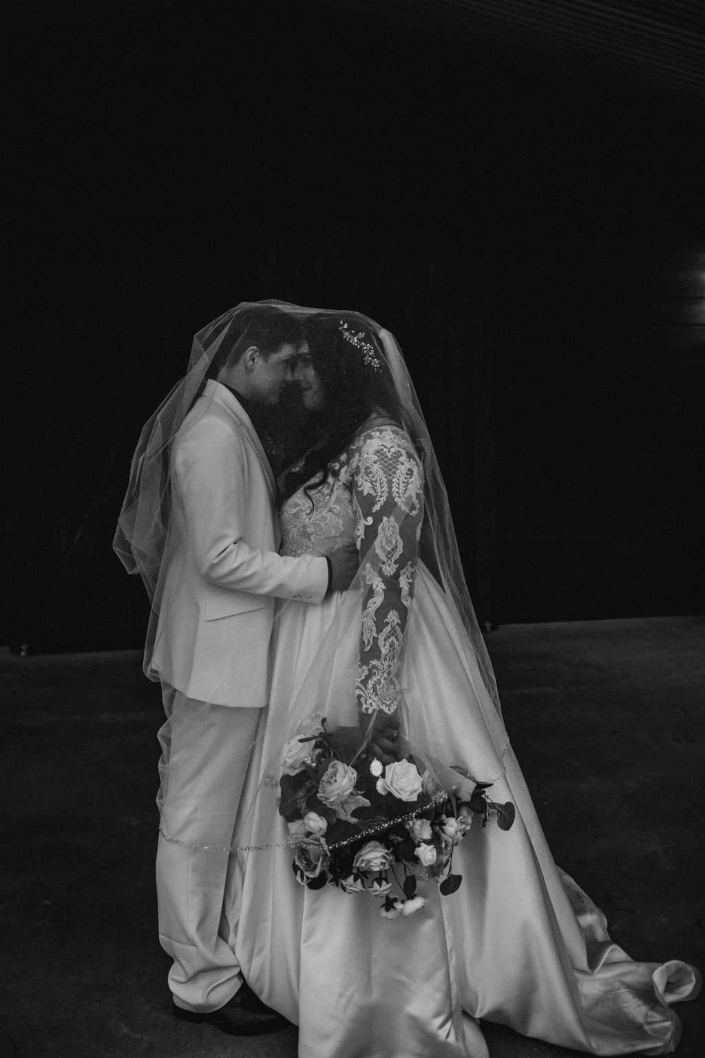 the texas brides are holding each other close under one of their veils shot with a photographer must haves