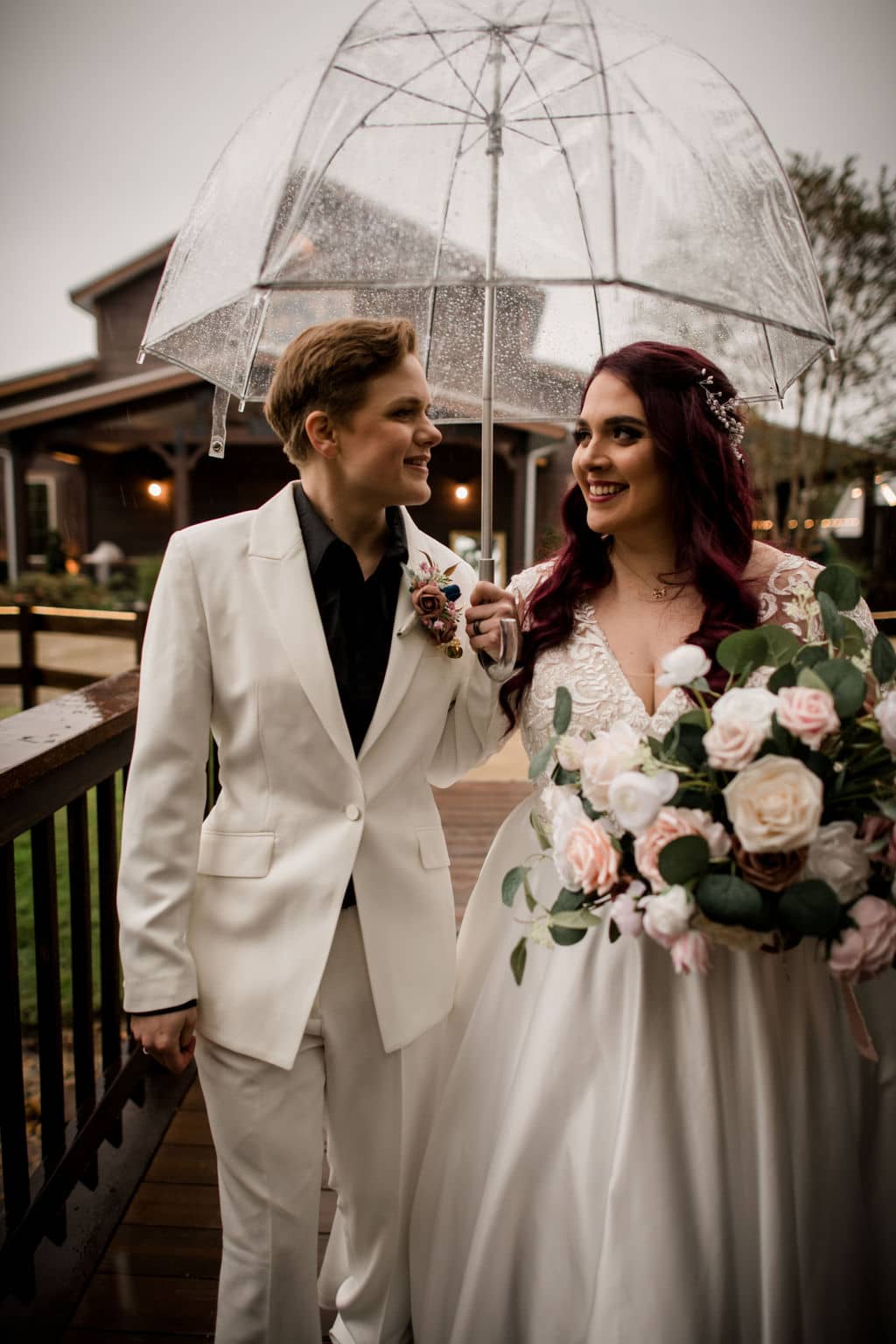 the two texas brides smile at each other under their clear umbrella