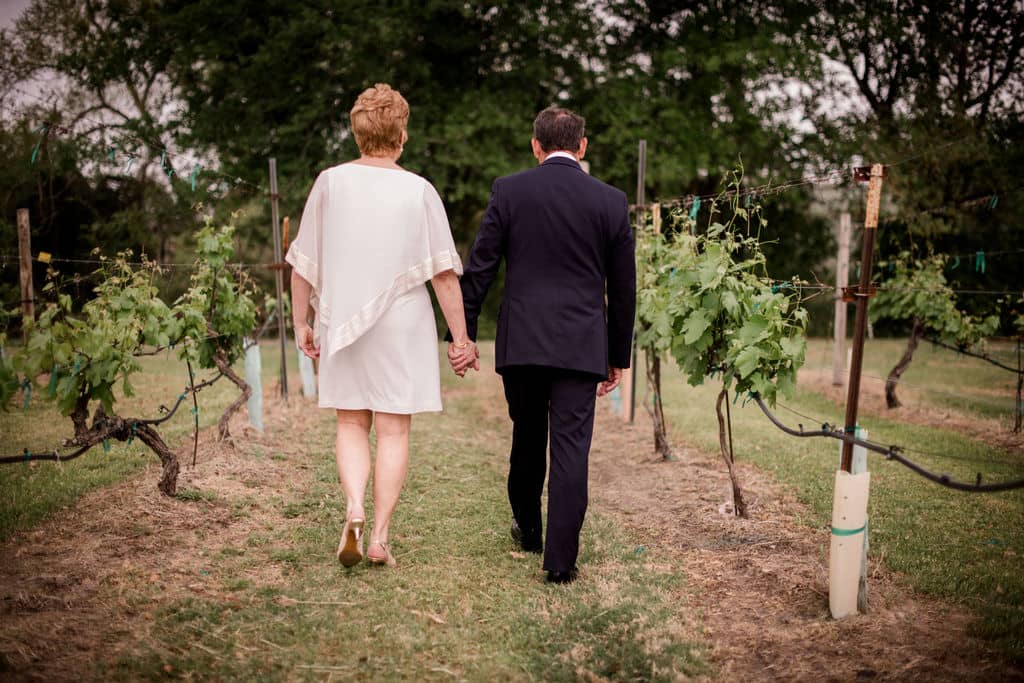 husband and wife walk the texas vineyards after their vow renewal ceremony