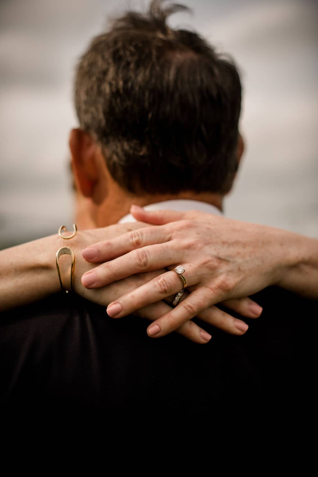 the bride wraps her arms around her grooms neck showcasing her accessories