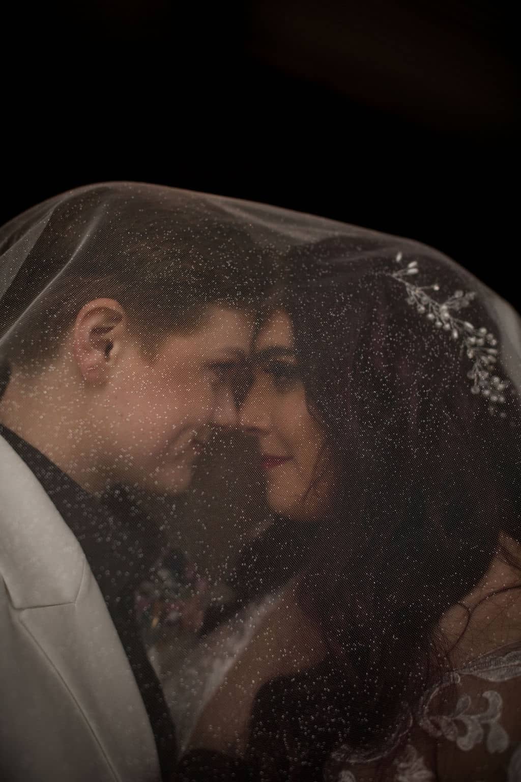 the two brides are staring into each other's eyes under the one of their veils