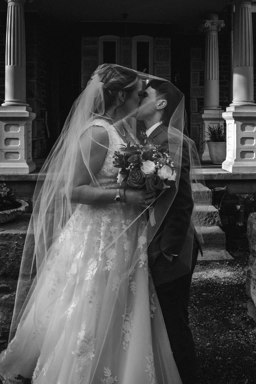 the two brides share a kiss under one of the bride's veils captured on a photographer must haves tool