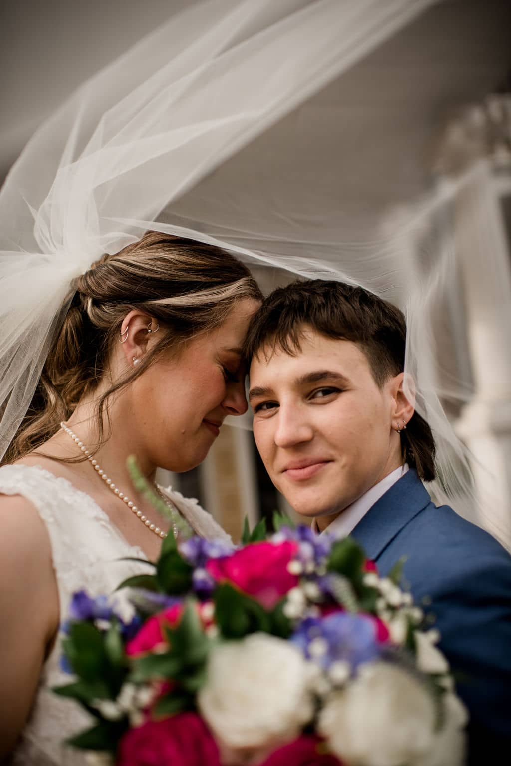 the texas brides are under one of the bride's veil while the other smiles at the camera captured on a photographer must haves tool