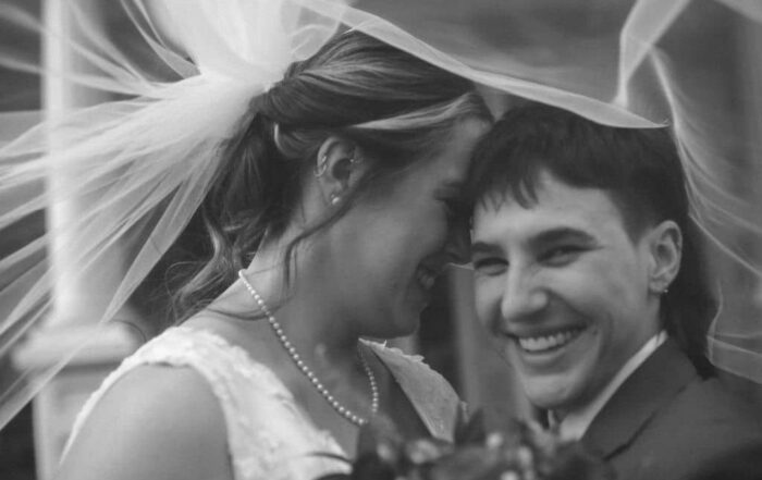 the texas brides are under one of the bride's veil while the other smiles at the camera captured on a photographer must haves tool