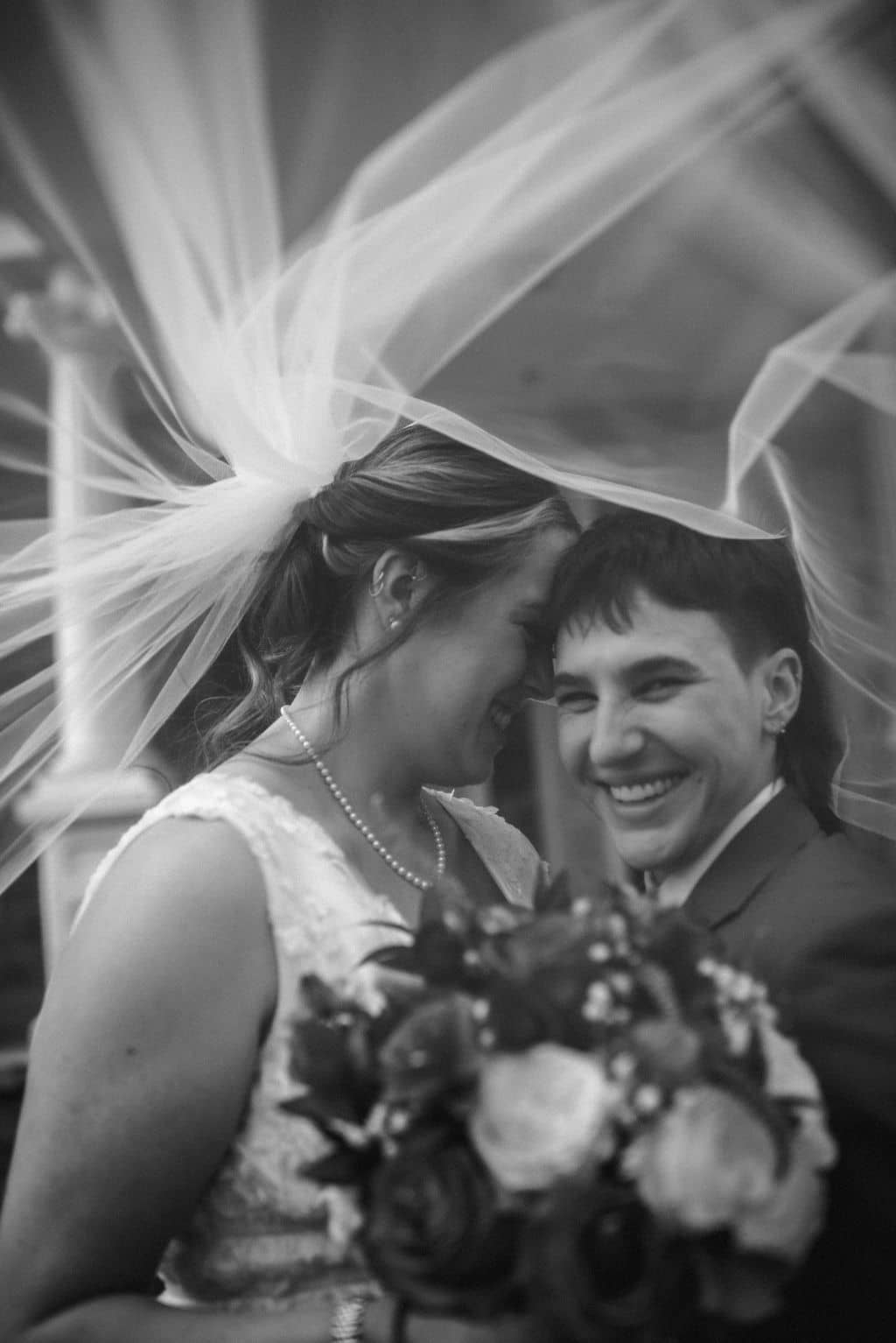 the texas brides are under one of the bride's veil while the other smiles at the camera captured on a photographer must haves tool